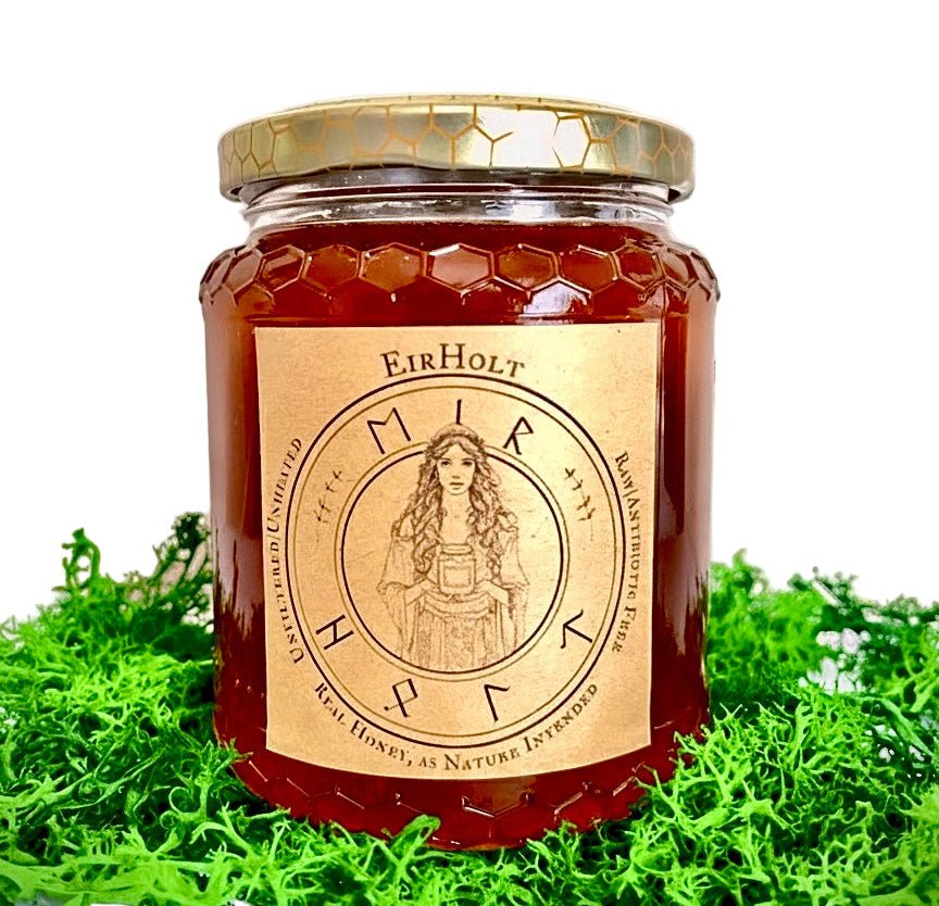 Jar of honey with a gold lid and 'Eir Holt' label on a green grass background