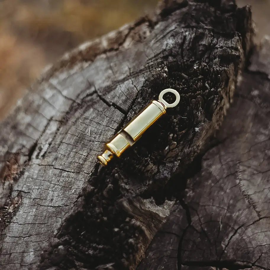 Gold metal whistle on a textured wooden surface