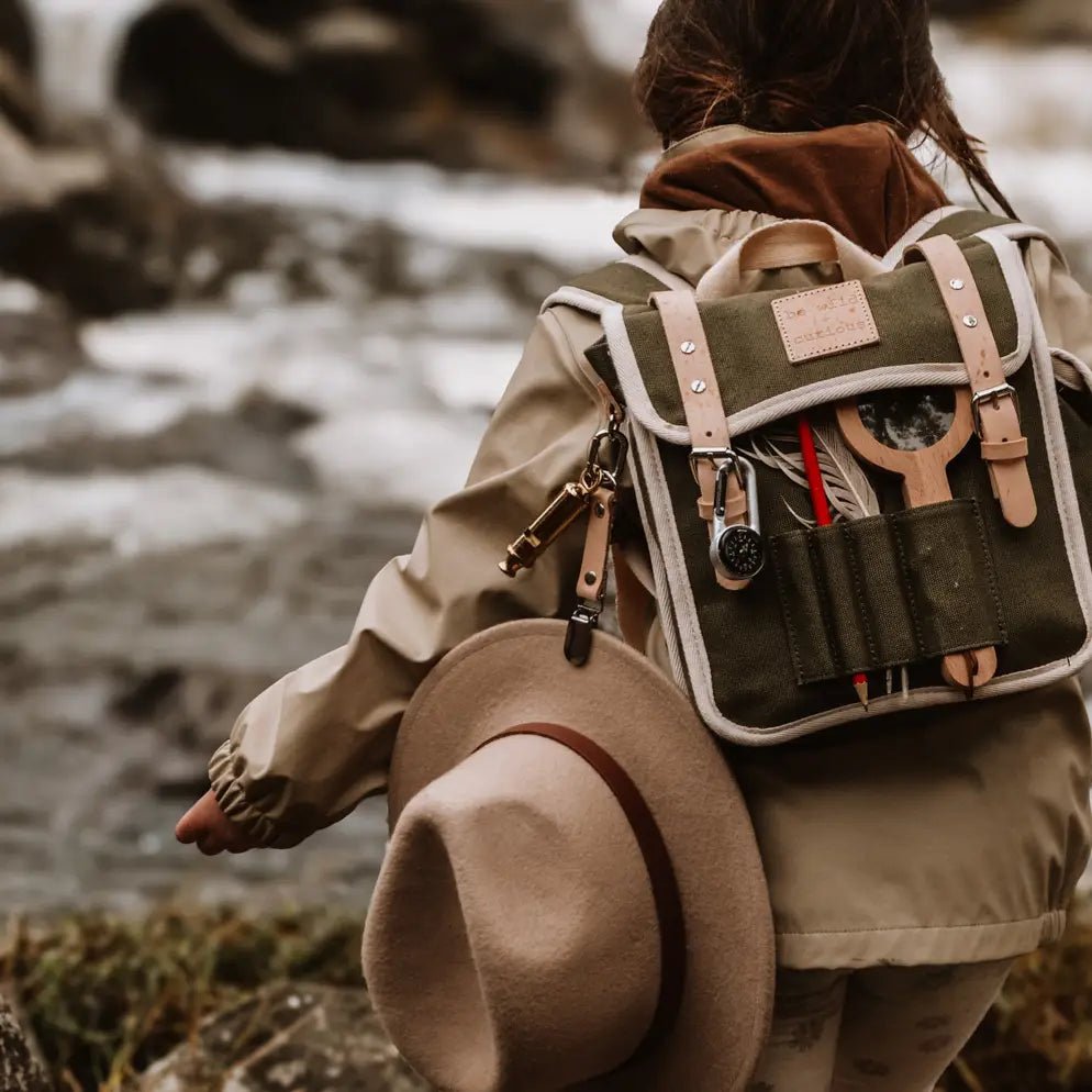Kid with a backpack and hat by a river