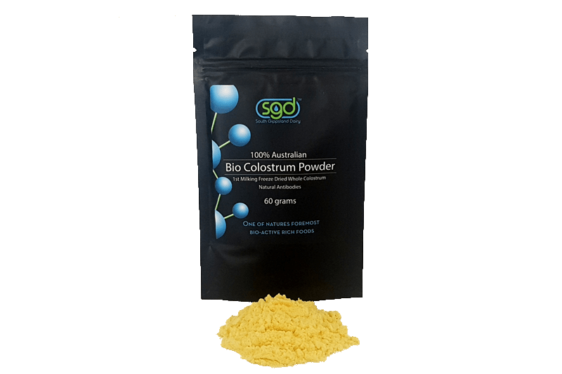 Black bag of SGD Bio Colostrum Powder with yellow powder on a green background