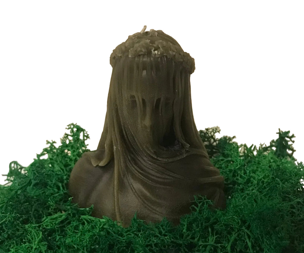 Veiled lady candle in charcoal on a bed of green moss with a neutral background